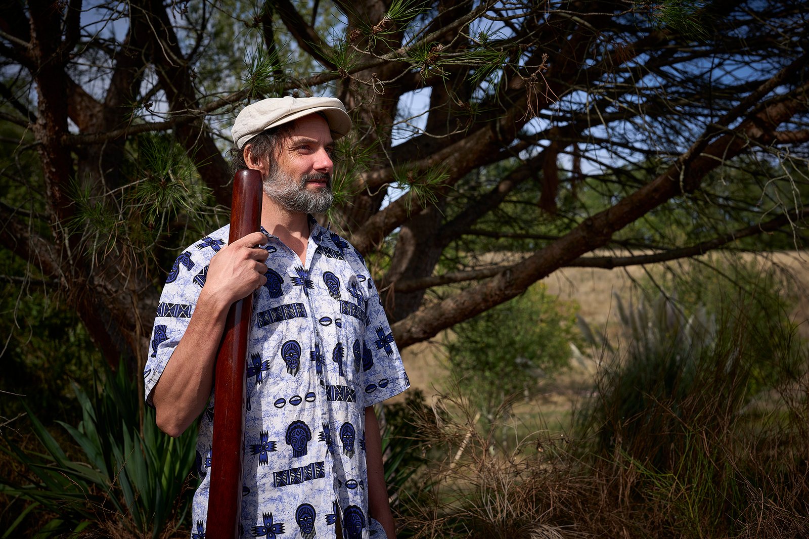Eliah Jasper playing the didgeridoo outdoors among trees
