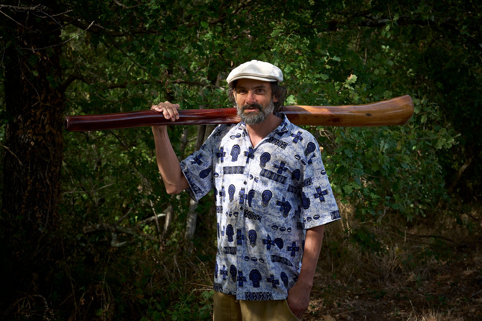 Eliah Jasper carrying his didgeridoo on his shoulder in the forest