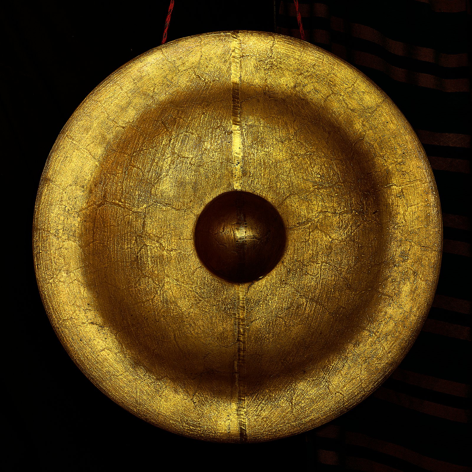 A large golden gong glowing in a dark room