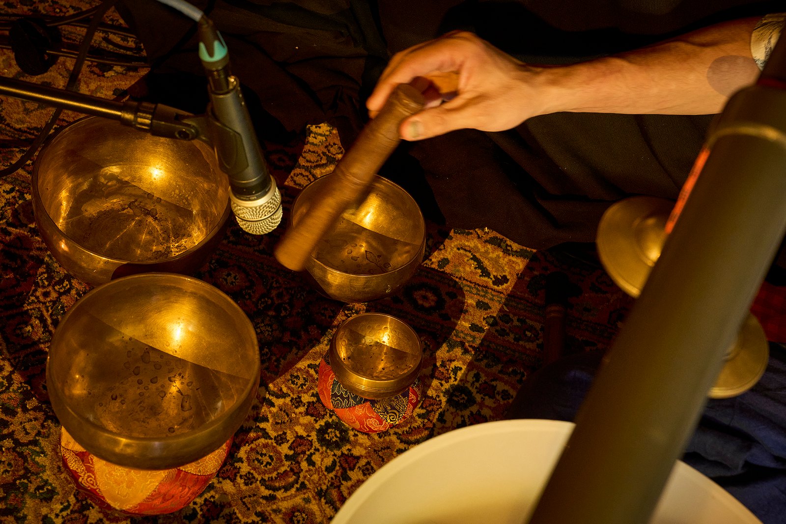 Hands of Eliah Jasper playing resonant instruments in warm light